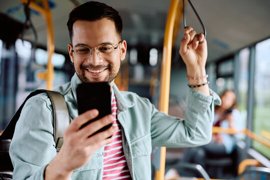 Happy man using app on cell phone while riding in bus.