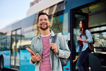 Young cheerful student arriving at bus station. - obrazy, fototapety, plakaty