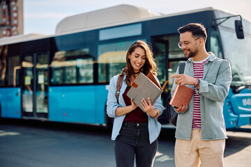 Young happy couple of students at public bus station.