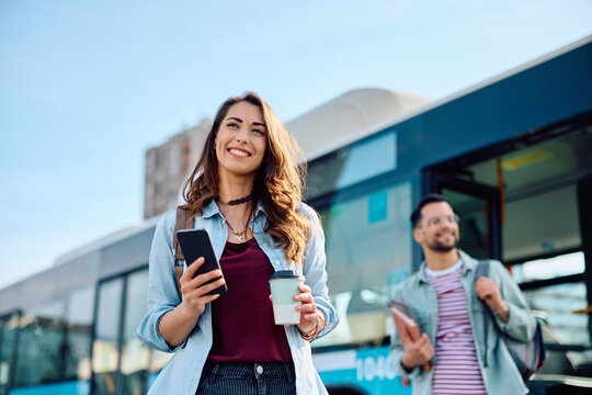 Young happy woman arriving at bus station. - Powered by Adobe