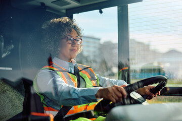Happy female bus driver behind the steering wheel.