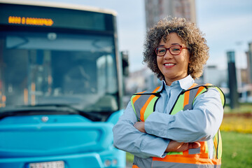 Portrait of confident female bus driver at station looking at camera.