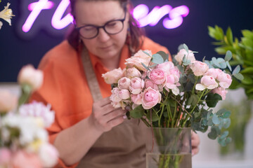 Working with delicate pink roses and peonies, the talented female florist crafts a breathtaking arrangement that is both timeless and memorable.
