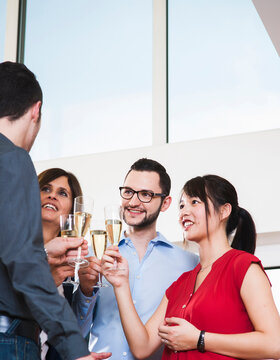Mature businesswoman toasting group of young business people with glasses of champagne, Germany