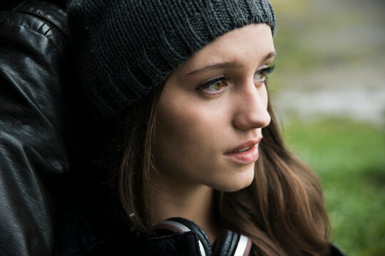 Close-up portrait of teenage girl outdoors, wearing hat and headphones around neck, Germany