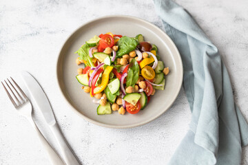 Vegetarian vegetable salad with chickpeas, tomatoes, red onions, cucumbers and lettuce. Vegetarian food rich in protein and fiber. 