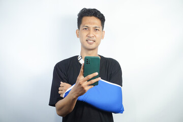 Young man in casual clothes with broken hand using cellphone to talk to doctor via video conference