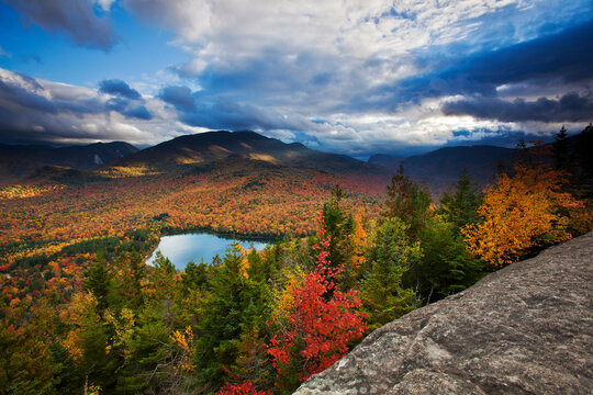 Vibrant autumn colours in Adirondack Park, with a view of Heart Lake and Algonquin and Wright peaks of the Adirondack Mountains; New York, United States of America