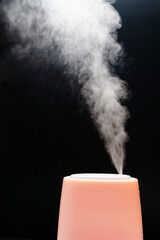 Steam from pink humidifier on a black background. 