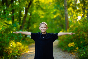 Outdoor portrait of a young boy standing on a park trail with arms outstretched; Edmonton, Alberta, Canada
