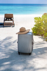 A suitcase and a straw hat against the backdrop of the landscape of the Maldives. Travel and tropical vacation concept