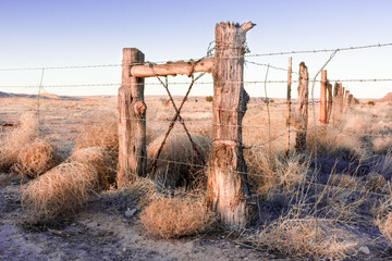 Weathered hand-hewn fence at sunset with barbed wire on a New Mexico ranch in the High Plains.