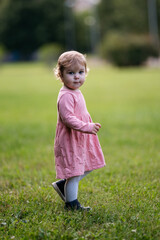 Portrait of caucasian toddler girl in park looking at camera.