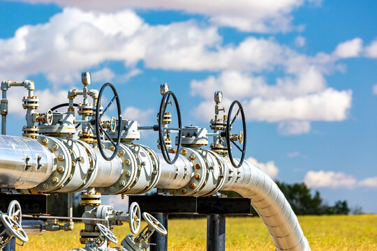 Oil pipeline with values, blue sky and clouds, West of Airdrie; Alberta, Canada