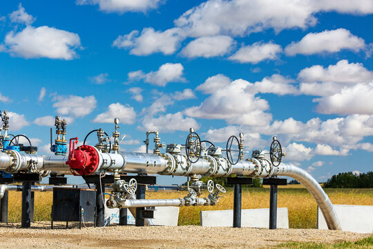 Oil pipeline with values, blue sky and clouds, West of Airdrie; Alberta, Canada