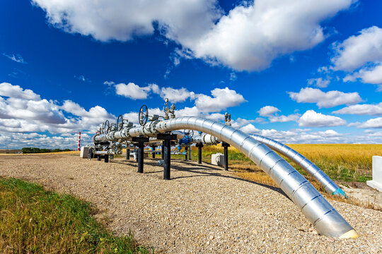 Oil pipeline with values, blue sky and clouds, West of Airdrie; Alberta, Canada