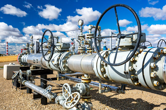 Oil pipeline with values, blue sky and clouds, West of Airdrie; Alberta, Canada