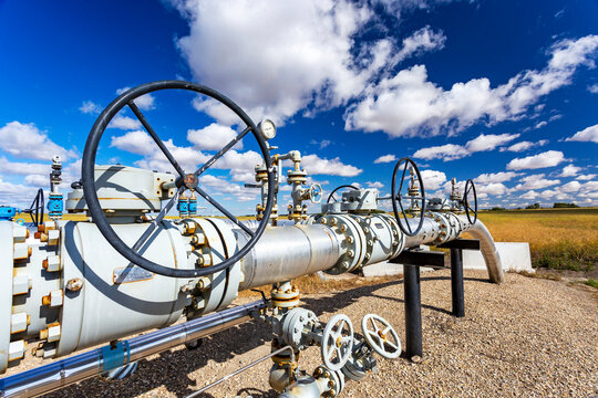 Oil pipeline with values, blue sky and clouds, West of Airdrie; Alberta, Canada