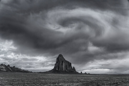 Clouds looking like a vortex above Shiprock in the high-desert plain of the Navajo Nation in New Mexico, USA, processed in Black and White; Shiprock, New Mexico, United States of America