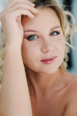 Naklejka premium portrait of a tattooed blonde in a white room. cosmetics for face and body. 