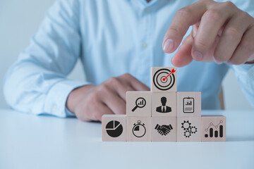 Male hand arranging wooden cubes with target icon for planning development leadership and customer target group concept. Business strategy, action plan, goal setting, achievement and objectives.