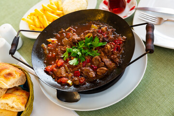 Traditional meat dish of Turkish cuisine is Sac Kavurma, cooked from lamb with vegetables in a special frying pan and ..decorated with herbs on top