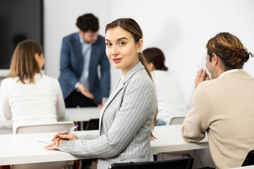 Cheerful woman turning around and looking at camera during advanced training course in auditorium