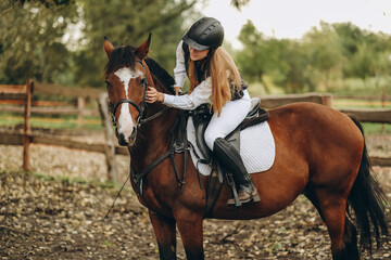 A young female jockey is sitting on her horse in show jumping training. Preparing for the...
