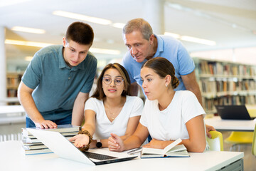 Group portrait of smiling positive engaged in research, working together in public library