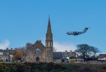 Atlas RAF aircraft carrier flying over the town of Lossiemouth and past the church spier as it comes in to land at RAF Lossiemouth 