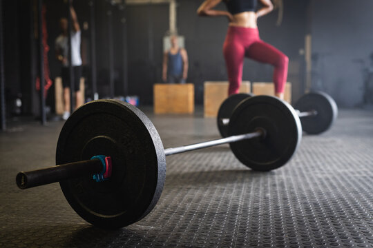 Barbells on floor in health club with people in background, copy space