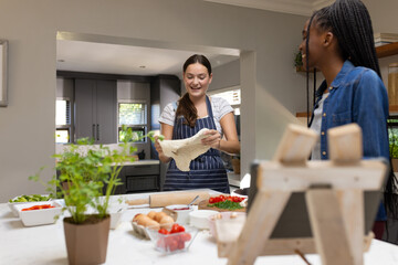 Happy diverse teenager girls friends making pizza in kitchen