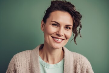 Fototapeta premium Portrait of a smiling woman looking at the camera while standing against green background