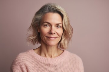 Portrait of a happy mature woman with short blond hair on a pink background