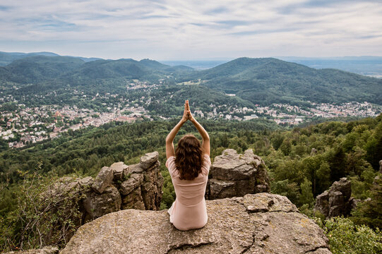 Frau beim Yoga mutig auf Felsen umgeben von Wald und Weitblick auf die Stadt Baden-Baden 