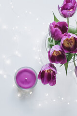A bouquet of tulips and a magenta candle with lights.