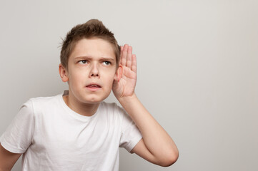 caucasian young boy dressed in the white t-shirt listening through the silence