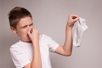 the boy closes his nose from the horrible stench of dirty socks - obrazy, fototapety, plakaty