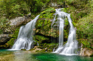 Fototapeta na wymiar Side view of fairytale Virje waterfall in Slovenia - Pluzna. Dreamy and beautiful natural double waterfall shot on long exposure.