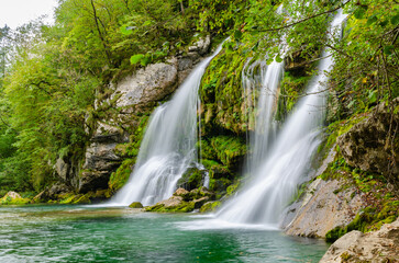 Fototapeta na wymiar Side view of fairytale Virje waterfall in Slovenia - Pluzna. Dreamy and beautiful natural double waterfall shot on long exposure.