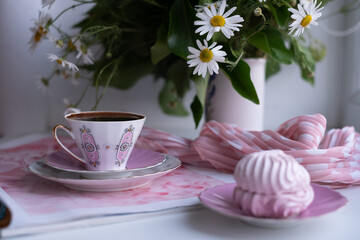 A gorgeous fragile white pink cup of coffee on a large soft pink napkin and a puffy airy pink...