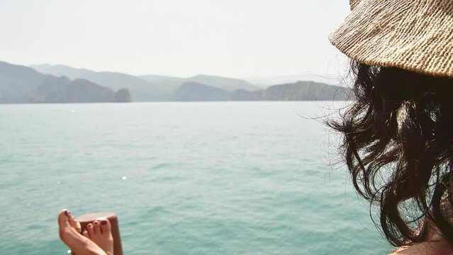 Caucasian woman relax lay on vacation on cruise ship deck enjoy sunny persian gulf panorama with rocky mountains cliffs. Oman holiday destination. Mirelas island tour.Musandam