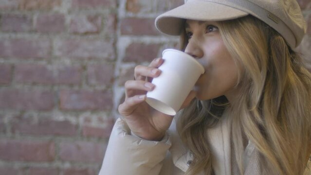A beautiful woman enjoys a hot chocolate while sitting in the cold air