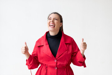 Woman in red coat on white background smiles with thumbs up