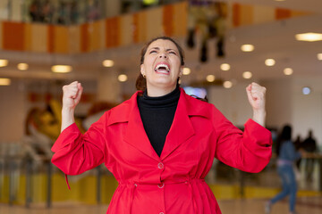 Euphoric woman poses with raised fists in unstoppable happiness