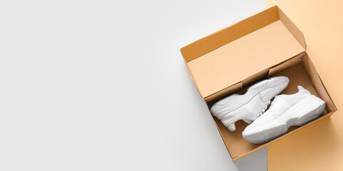 Cardboard box with sports shoes on color background with space for text
