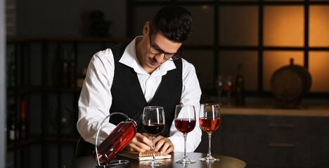 Young male sommelier tasting sorts of wine in cellar