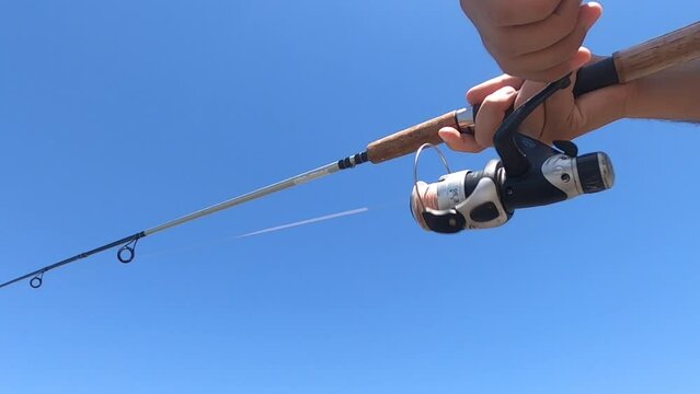 hombre girando manivela de un reel de pesca