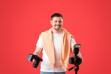 Male photographer with professional cameras on red background