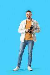 Male photographer with professional camera on blue background